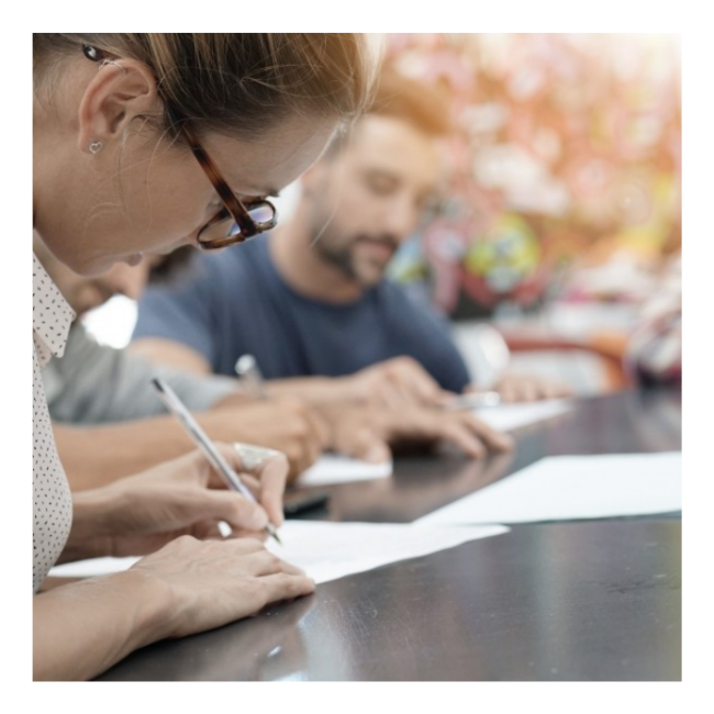 Woman writing on piece of paper at a table