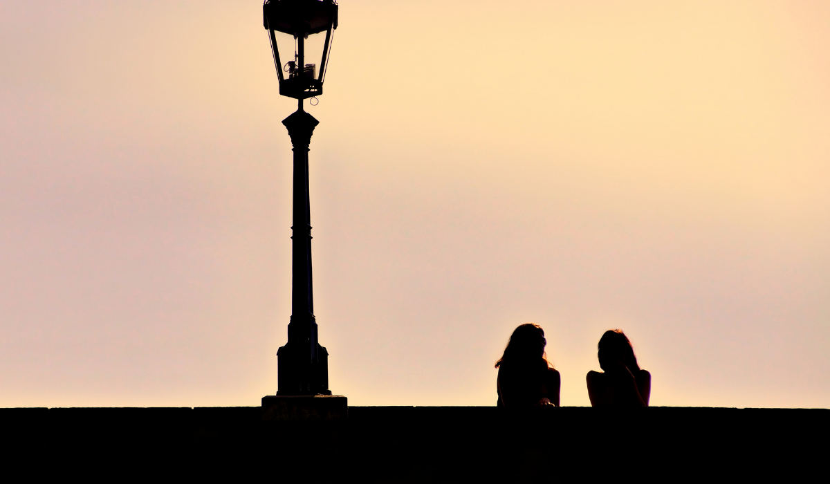 Two women talking on bridge at sunset