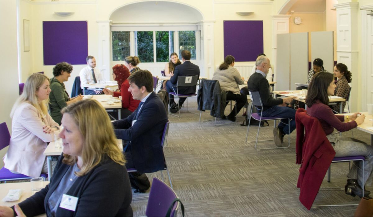 Students and mentors sitting at tables in the WoodLegh room