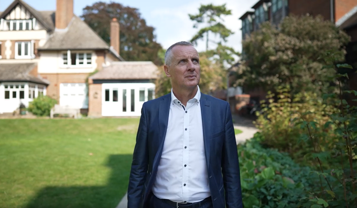 Gordon in the Lucy Cavendish gardens. He is wearing a blue suit jacket and white shirt