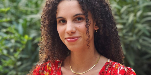 Imani Thompson's headshot. Green plants in the background